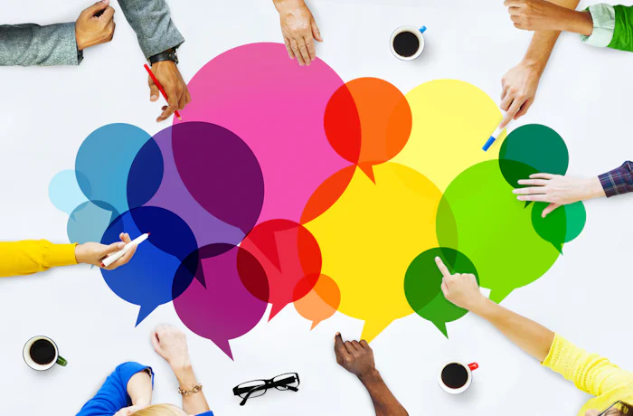 Brightly colored speech bubbles on a table with people's hands pointing to different ones